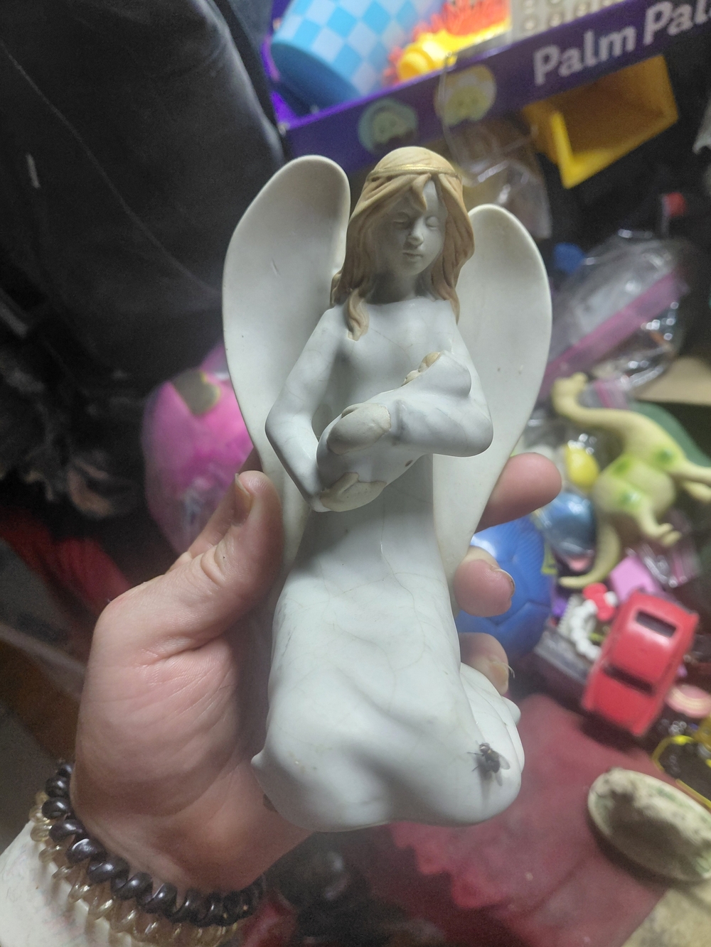 marbled kneeling angel figurine holding a small bundle, detailed with blonde...